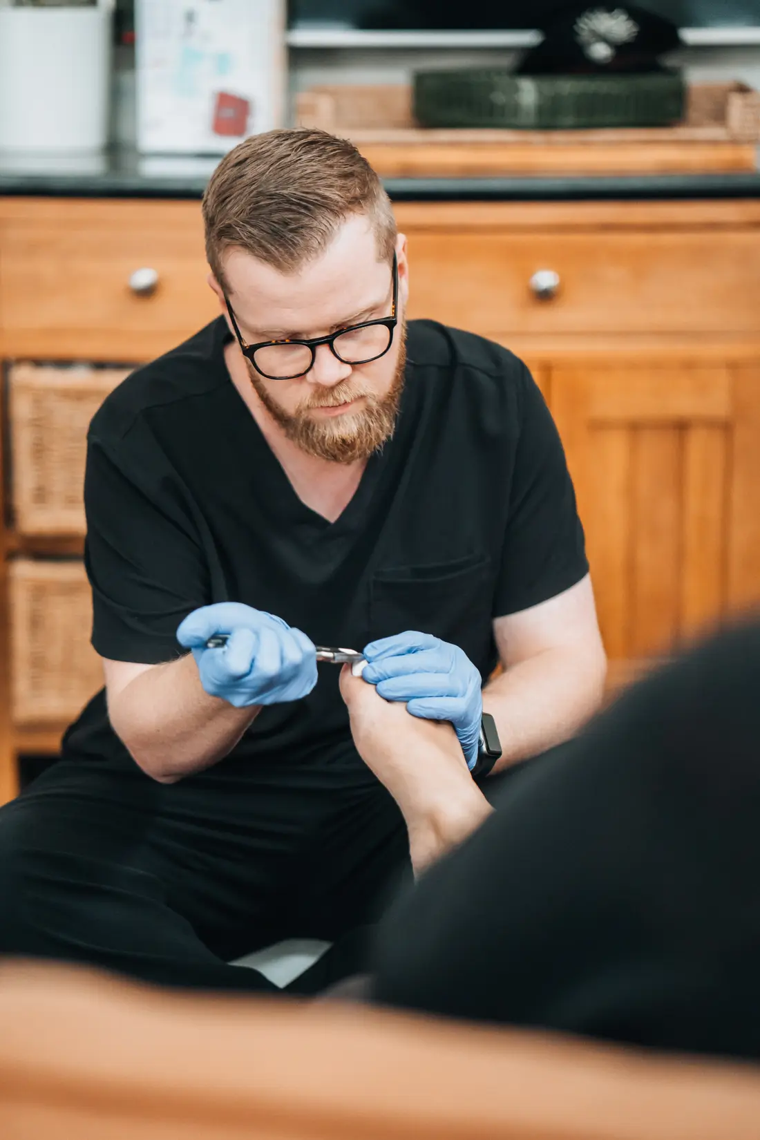 Podiatrist trimming toenails during general foot care at home